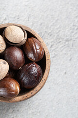 Dried Indian spice whole nutmeg in wooden bowl close-up on gray background top view with copyspace
