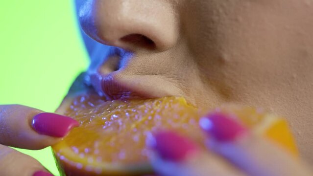 Zbliżenie marko na kobiece usta w czasie jedzenia 
 owocu pomarańczy