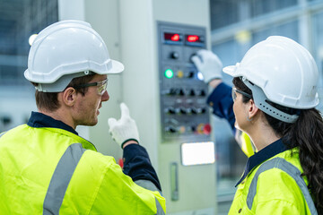 Male and female engineers in neat work clothes prepare and control the production system of large...