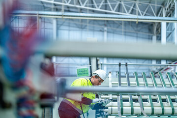 Male and female engineers in neat work clothes prepare and control the production system of large modern machines in a factory producing industrial technology products.