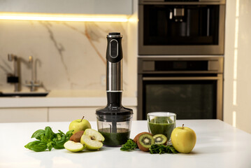 Electric immersion blender on kitchen table with green vegetables