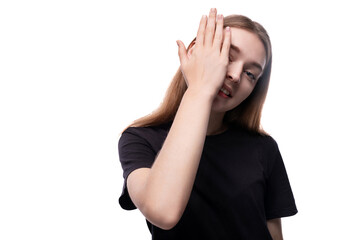 A fair-haired teenage girl in a black T-shirt covered her face with her hand