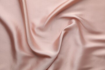 Crumpled pink silk fabric as background, top view
