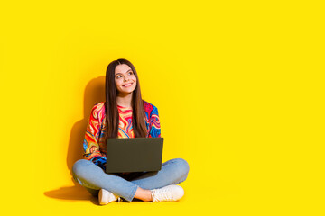 Naklejka premium Full size photo of pretty young girl look empty space netbook wear trendy colorful outfit isolated on yellow color background