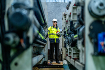 female engineers in neat work clothes prepare and control the production system of large modern machines in a factory producing industrial technology products.