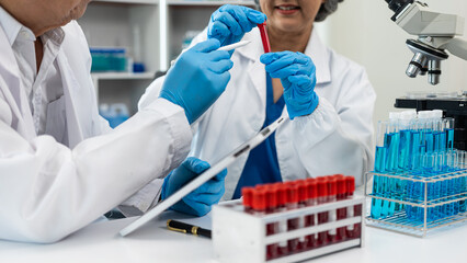 Two senior Asian scientists working in a laboratory are scientists researching biology and...