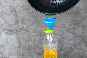 Close-up Pour used cooking oil from pan into plastic bottle. Old or used cooking oil can be...