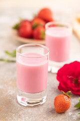 Sweet strawberry liqueur in glass on a gray concrete background. side view, selective focus