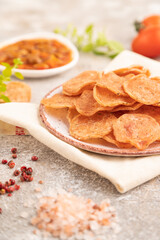 Slices of dehydrated salted meat chips on gray concrete, side view, selective focus