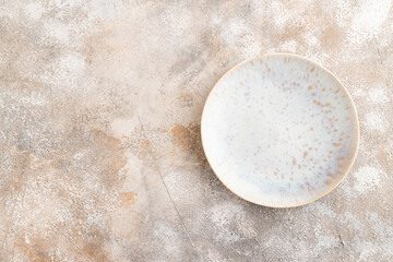 Empty blue and gold ceramic plate on brown concrete background. Top view, copy space