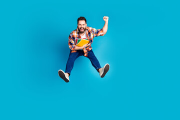 Obraz premium Full length portrait of nice young man jump raise fist wear shirt isolated on blue color background