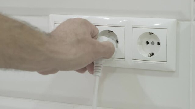 man take out plug Into electrical socket, slow motion
