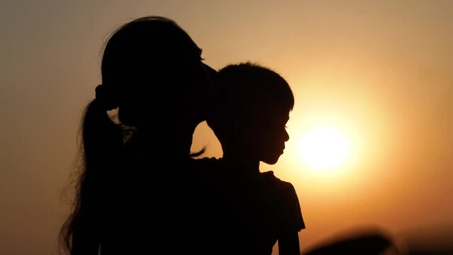 An Asian boy and her mom sitting under the hot sun trying to cool her body using a hand fan.