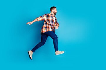 Full length portrait of nice young man jump run empty space wear shirt isolated on blue color background