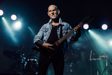 Obraz premium Senior rock guitarist with electric guitar in jeans jacket on stage.