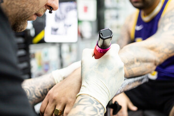 An unrecognizable artist performs a tattoo on a man's forearm with a wireless machine.Concept of...