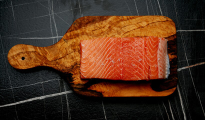 Raw salmon on olive tree cutting board