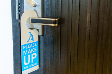 Please make up the room sign on the closed brown door at hotel.