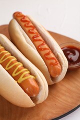 Tasty hot dogs with ketchup and mustard on white table, closeup