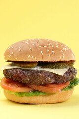 Burger with delicious patty on yellow background, closeup