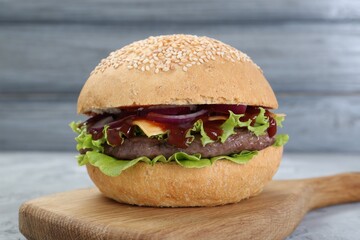 Delicious cheeseburger with lettuce, onion, ketchup and patty on table, closeup
