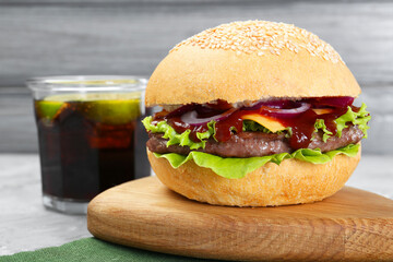 Delicious cheeseburger and drink on grey table, closeup