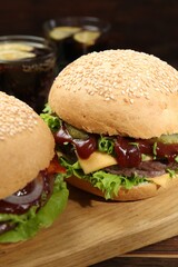 Board with delicious cheeseburgers on table, closeup