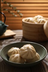 Delicious bao buns (baozi) in bowl on wooden table, closeup