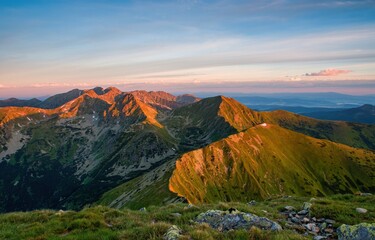 Summer in the polish tatra mountains, mountain peaks in Western Tatras mountains in Poland and Slovakia with other peaks scenery, hiking trail, relaxing people on stone and blue sky with clouds.