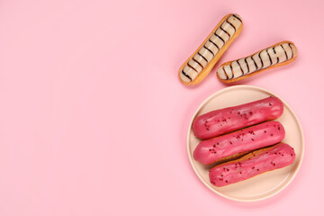 Delicious eclairs covered with glaze on pink background, flat lay. Space for text