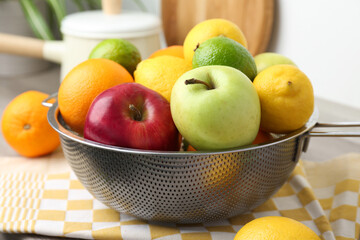 Metal colander with different fruits on table, closeup