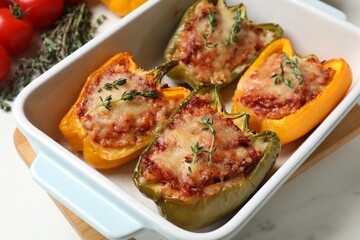Tasty stuffed peppers in dish on white table, closeup