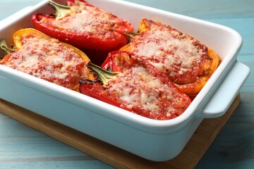 Tasty stuffed peppers in dish on light blue wooden table, closeup