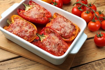 Tasty stuffed peppers in dish and ingredients on wooden table