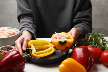 Woman making stuffed peppers with ground meat at white table, closeup