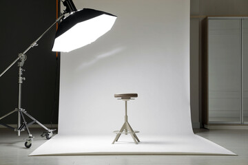 White photo background, stool and professional lighting equipment in modern studio