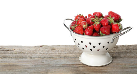 Colander with fresh strawberries on wooden table against white background. Space for text