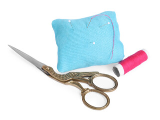 Pincushion with sewing pins, needle, scissors and spool of thread isolated on white