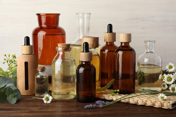 Aromatherapy. Different essential oils and flowers on wooden table