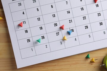 Timetable. Calendar page and drawing pins on wooden table, top view