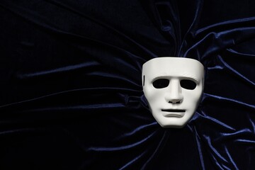 Theater arts. White mask on blue fabric, top view. Space for text