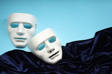 Theater arts. White masks and fabric on light blue background, above view. Space for text