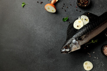 Dried mackerel herring on a black cutting board on a black background
