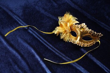Theater arts. Golden venetian carnival mask on blue fabric, top view