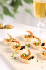Delicious canapes with shrimps and black caviar on table, closeup