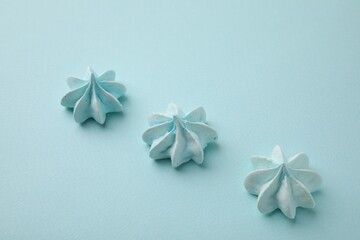 Delicious meringue cookies on light blue background, above view