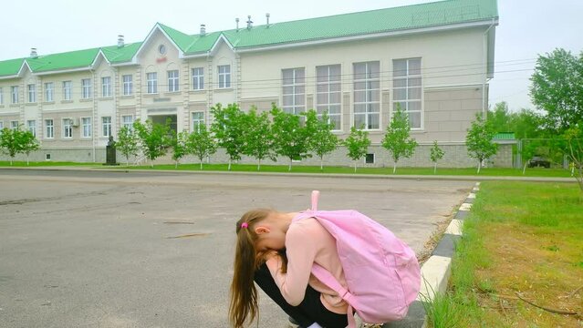 Upset school girl. Back to school. Child girl with backpack has bad emotions because of mark and that children are bullied. Primary school