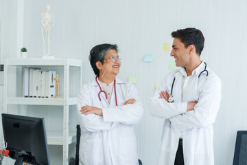 Fototapeta premium Expert in healthcare converses with medical trainee, both displaying engaging smiles in a clinical setting. Conversational exchange between seasoned practitioner and learner in hospital environment.