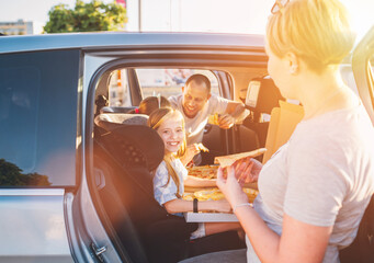 Positive smiling girl in child car seat while family car trip brake stop eating just cooked Italian...