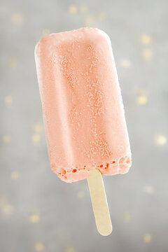 Close-up of a strawberry Popsicle in front of a grey polka dot background